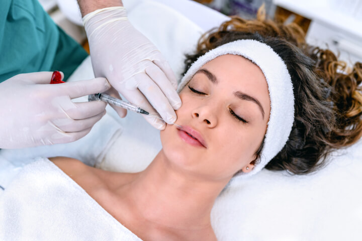 woman receiving an injection of dermal fillers in her face