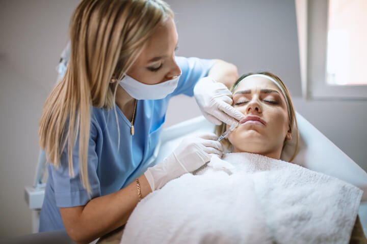 woman receiving injection of dermal fillers in her lips