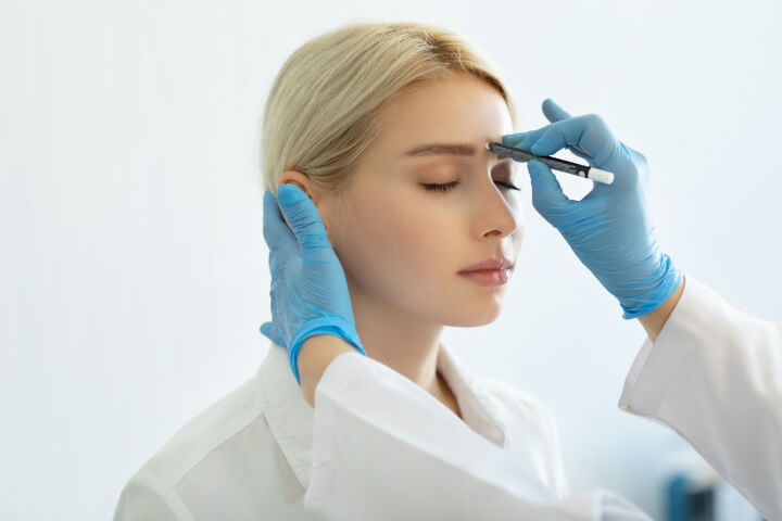 woman preparing to receive an injection of botox in her forehead