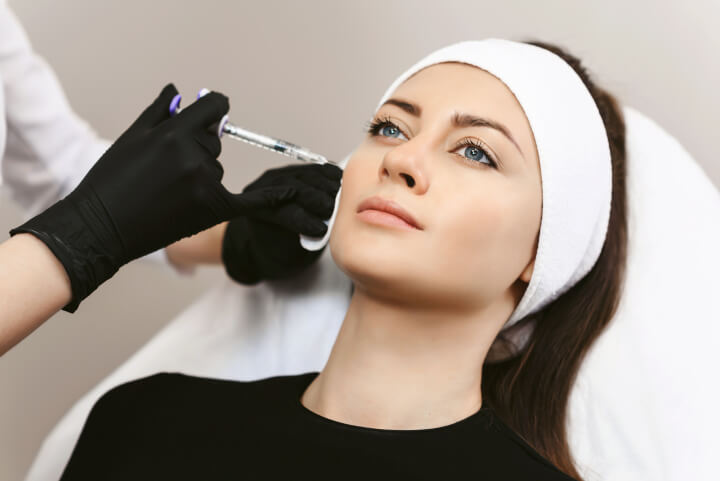 woman receiving an injection of dermal fillers by professional medical doctor for her marionette lines