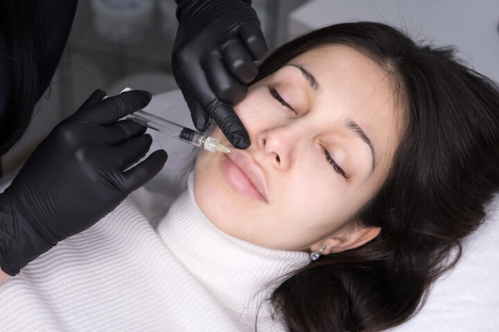 woman receiving a collagen dermal fillers in her lips by medical doctor