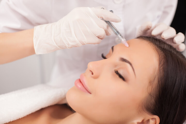 woman receiving an injection of dermal fillers in her forehead