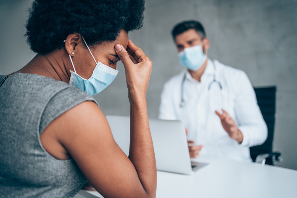 Young doctor talking to a black female patient with migraine